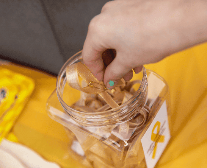 white female removing gold ribbon from clear plastic container