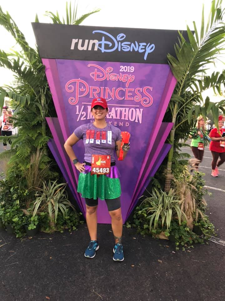 Disney Princess Half Marathon runner in front of sign