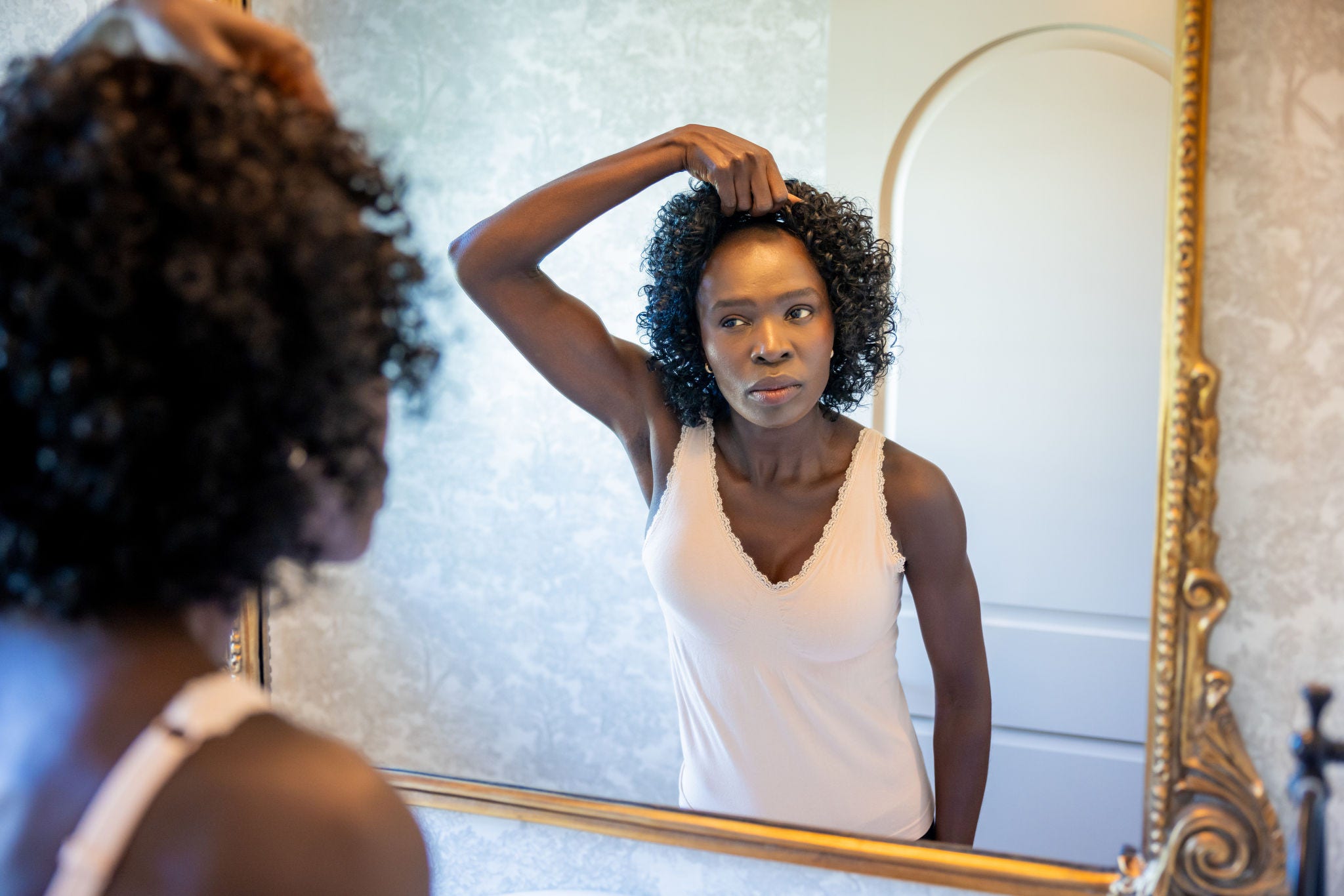 woman takes off wig in mirror