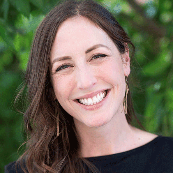 Headshot of a woman with brunette hair, smiling outdoors