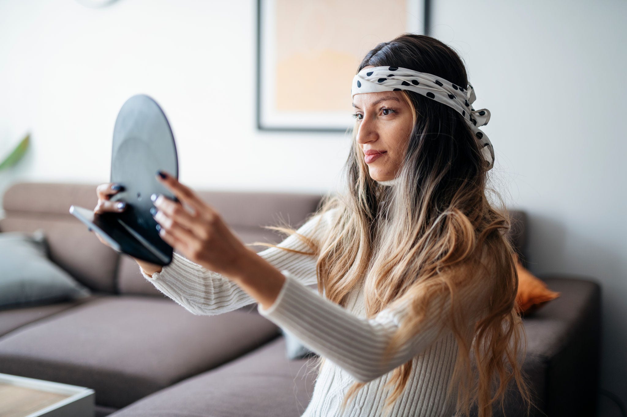 Person with cancer looking in mirror wearing wig styled with scarf