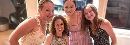 A group of four women together, smiling for a photo,