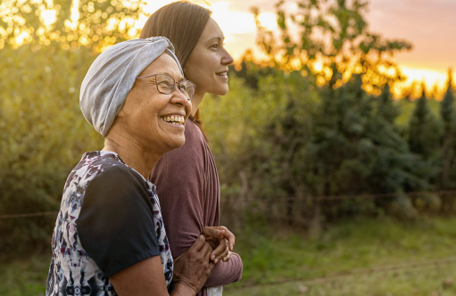 Two women smiling and embracing outdoors at sunset