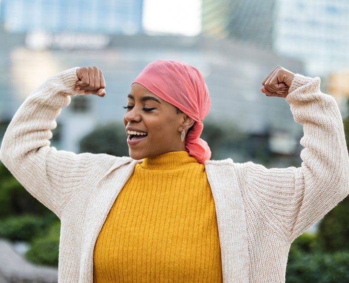 An Woman flexes her arm muscles wearing a pink bandana in support of breast cancer awareness