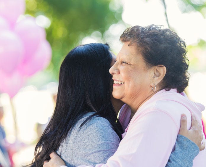 A woman lovingly hugs her mother during an event, highlighting the bond and solidarity in the fight against cancer.