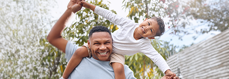 Image of a father holding his son on his shoulders both smiling