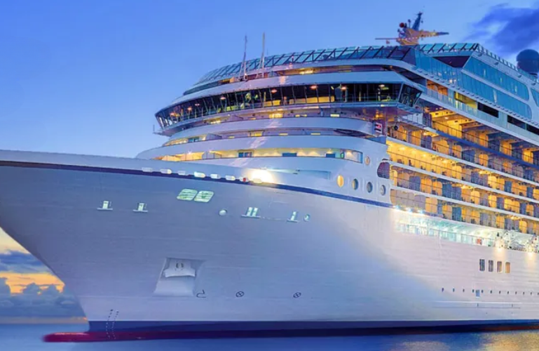 Large luxury cruise ship sailing at sunset with illuminated decks and a calm ocean backdrop