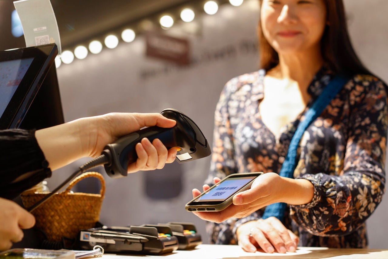 Customer using mobile payment at a retail checkout with a handheld scanner