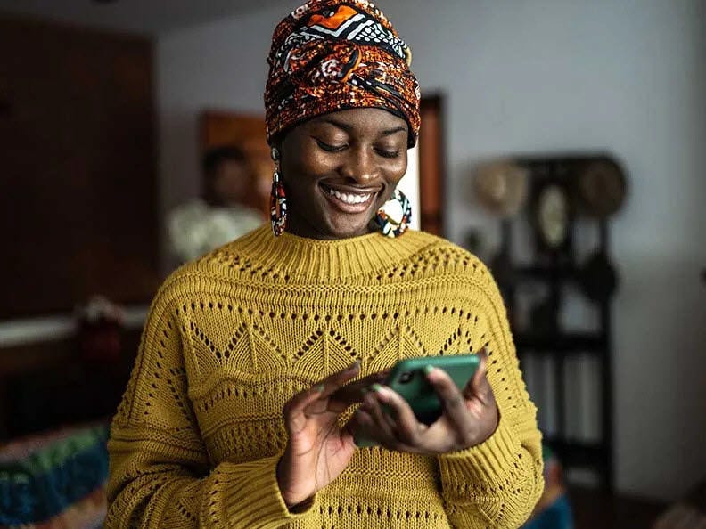 Smiling woman in a yellow sweater using her phone