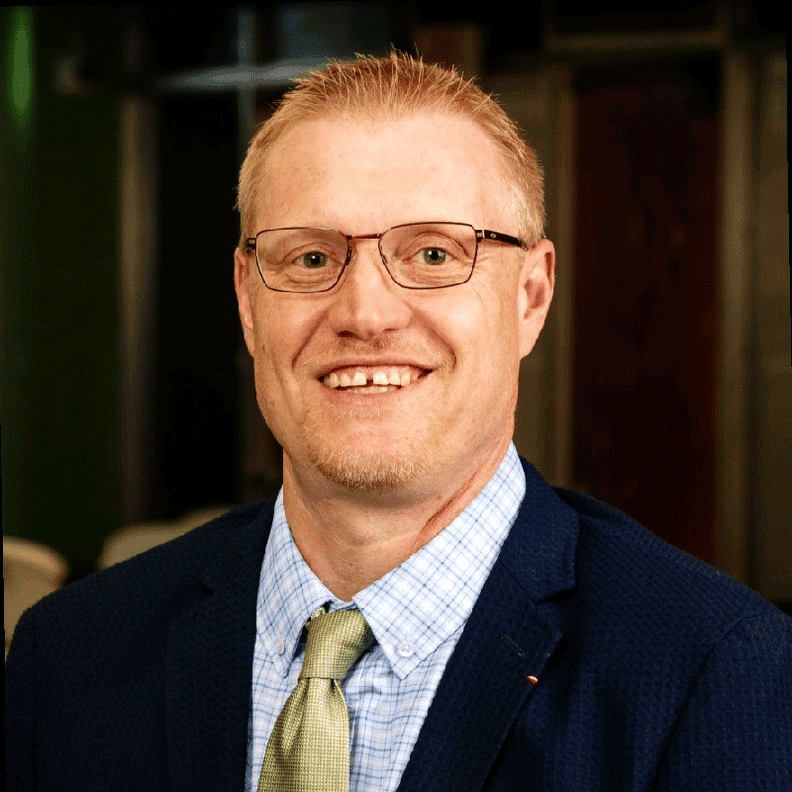 Smiling man in suit and glasses headshot.