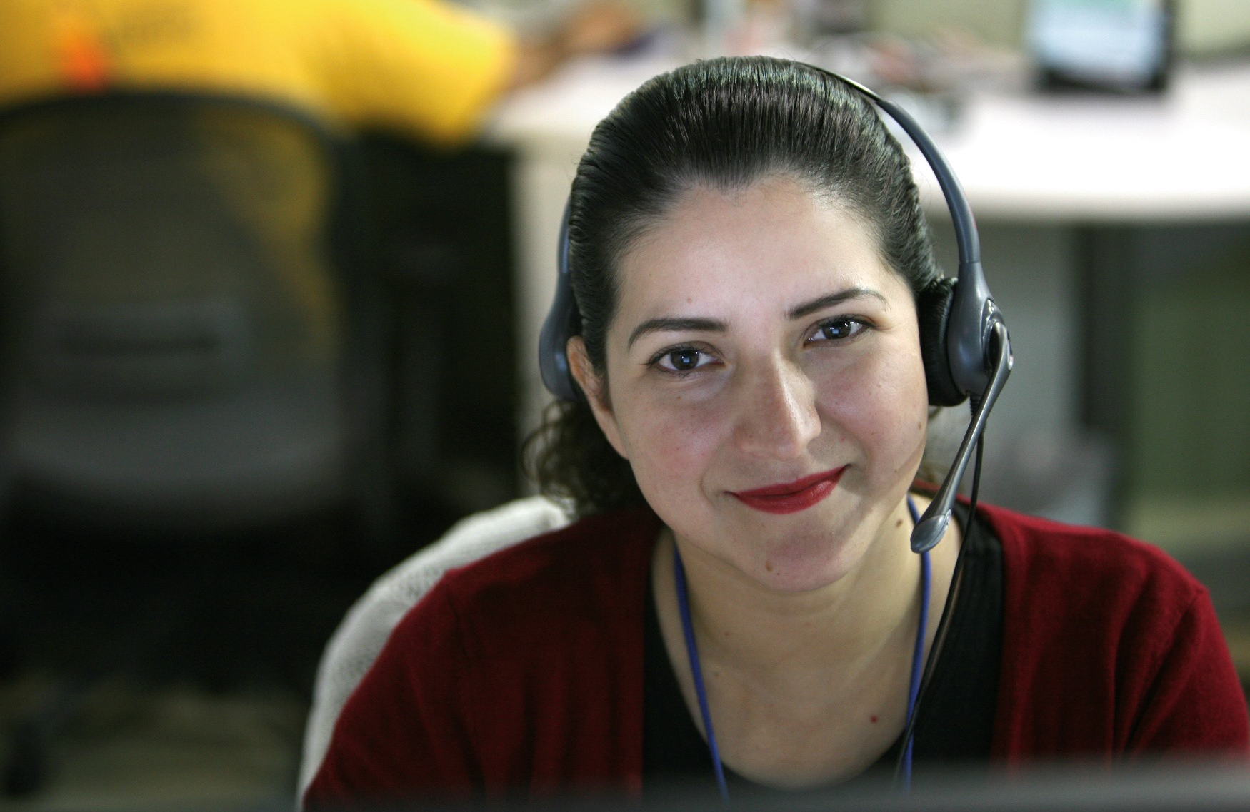 A female call center agent smiles while wearing a headset