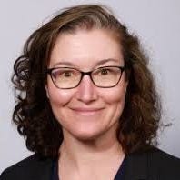 woman with reddish loose curls and dark glasses in v-neck