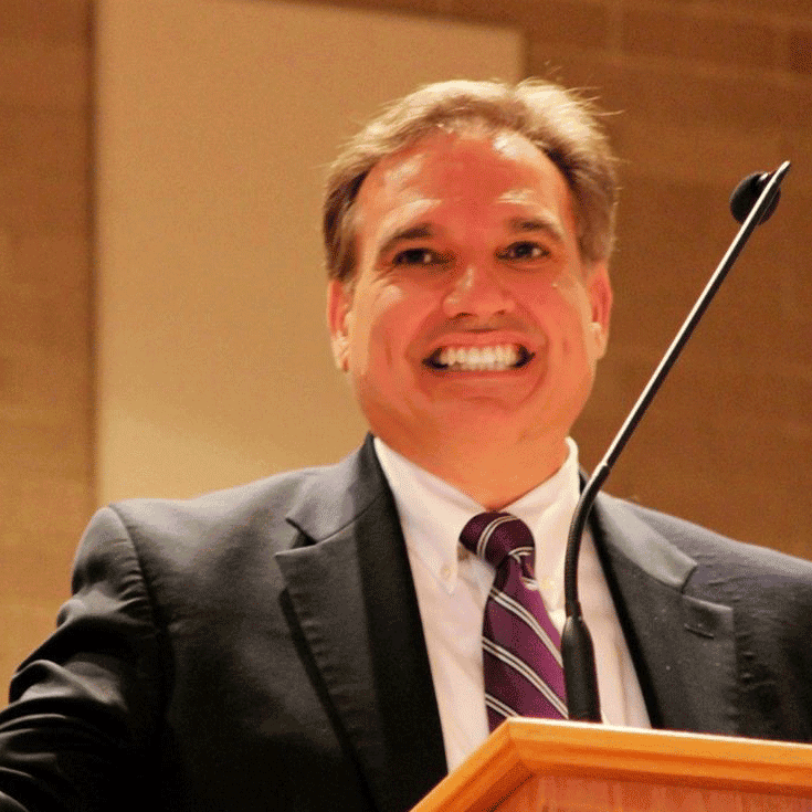 Smiling man in suit speaking at podium