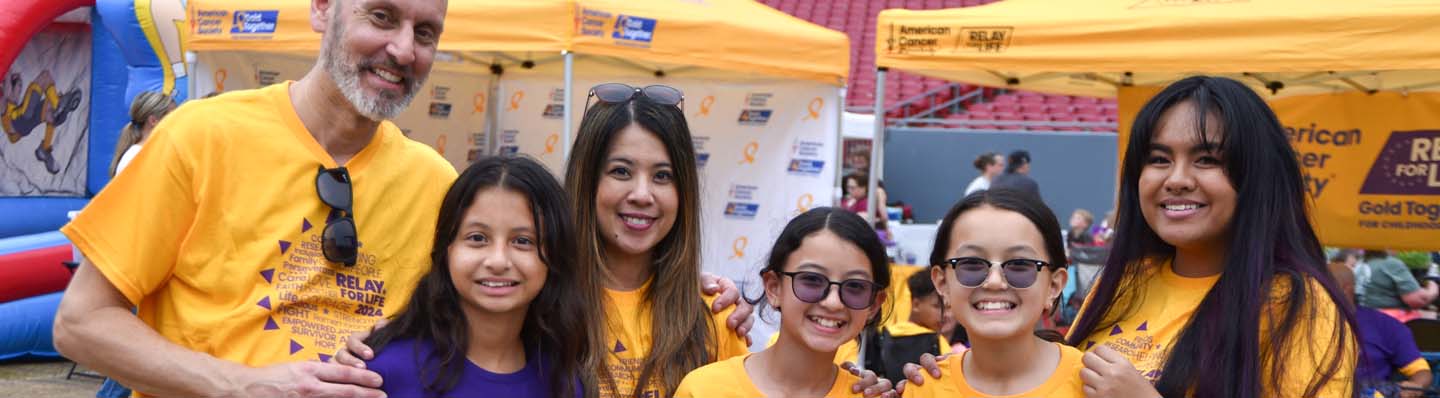 A family posing for an image at a gold together relay for life event
