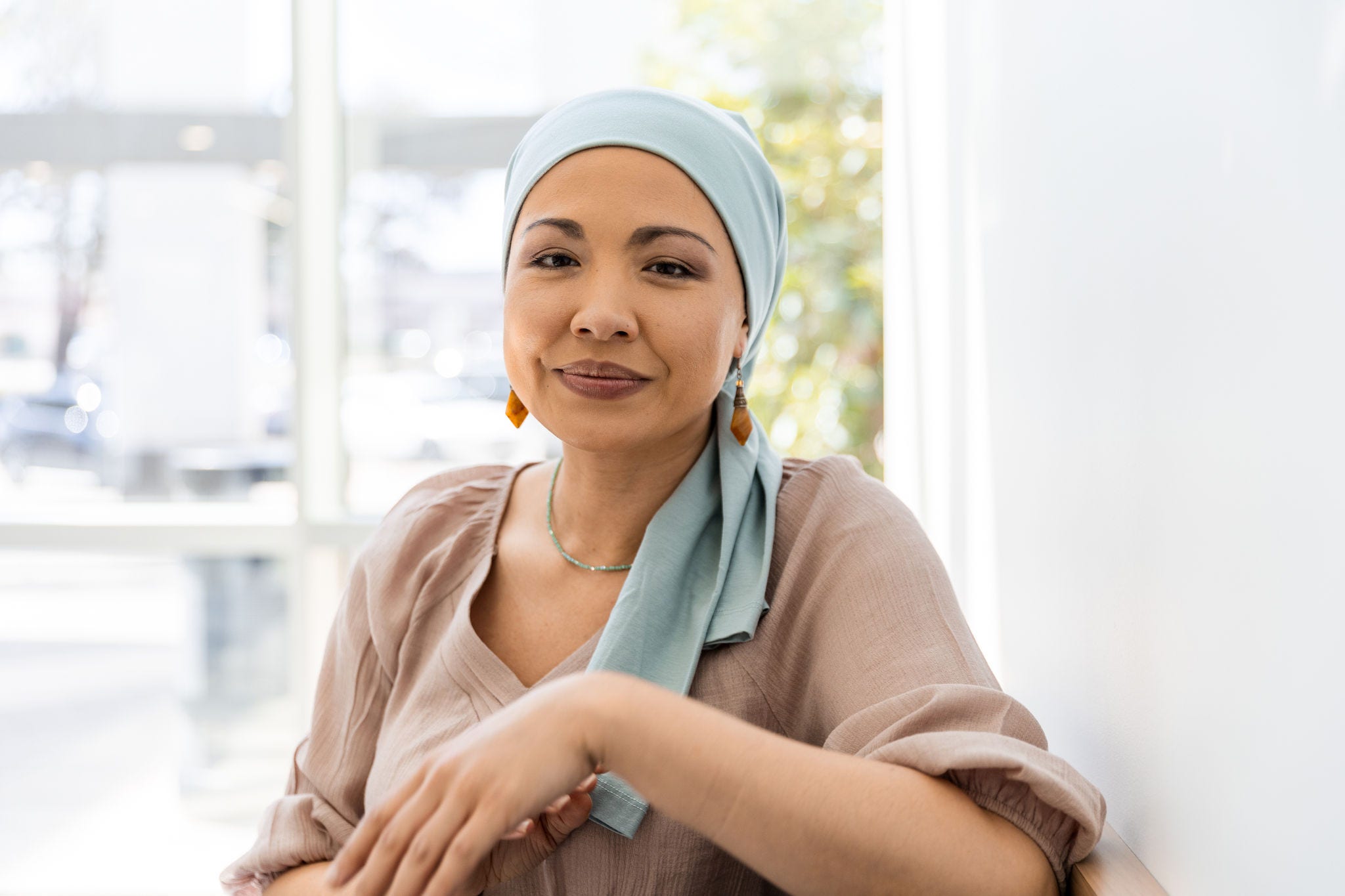 The mid adult female cancer patient smiles for the camera to have a close up photo taken for the hospital.