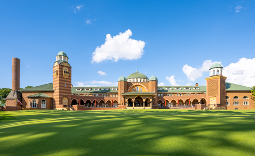 Historic clubhouse at Medinah Country Club with lush green lawn under a clear blue sky