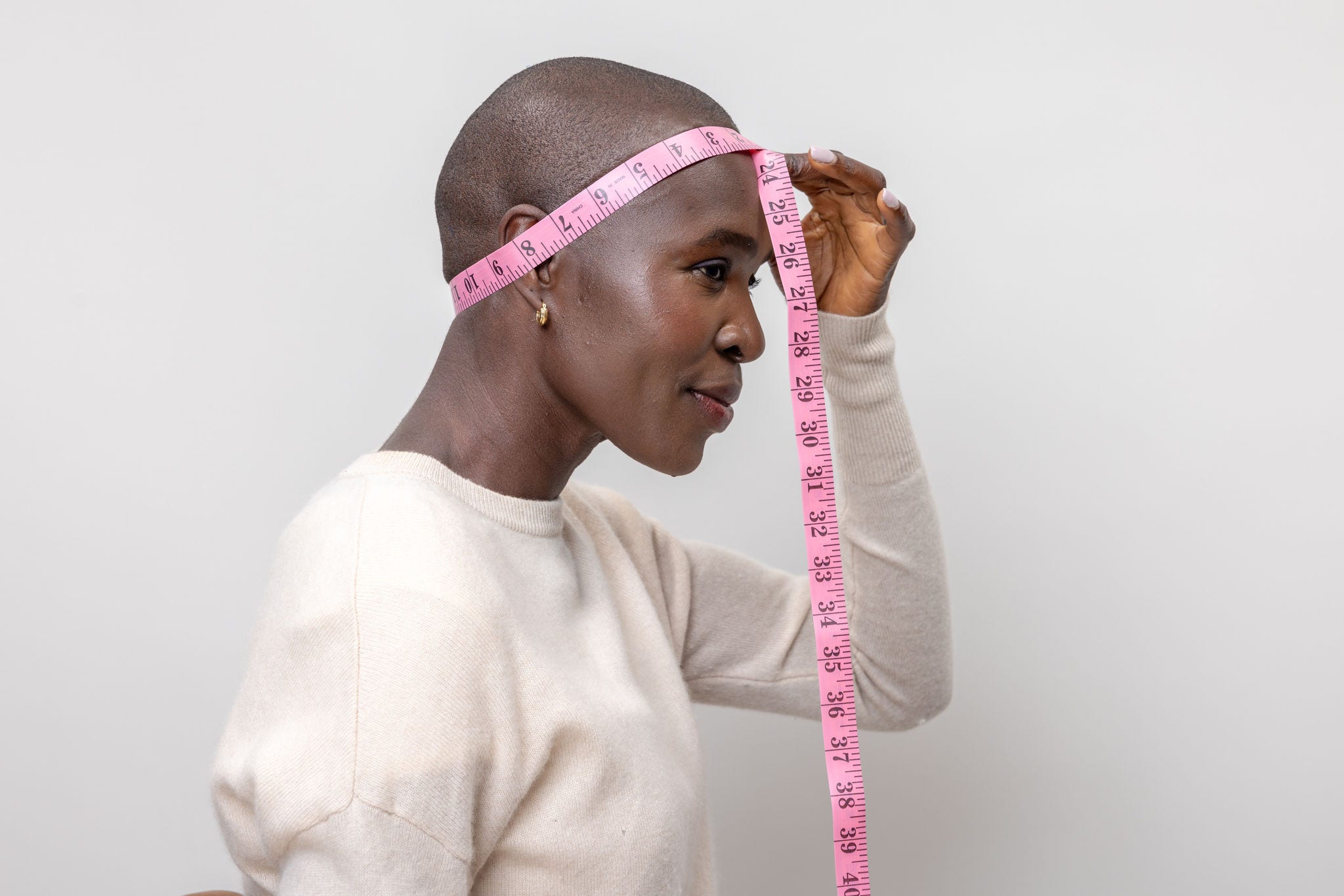 woman measures head back to front with measuring tape