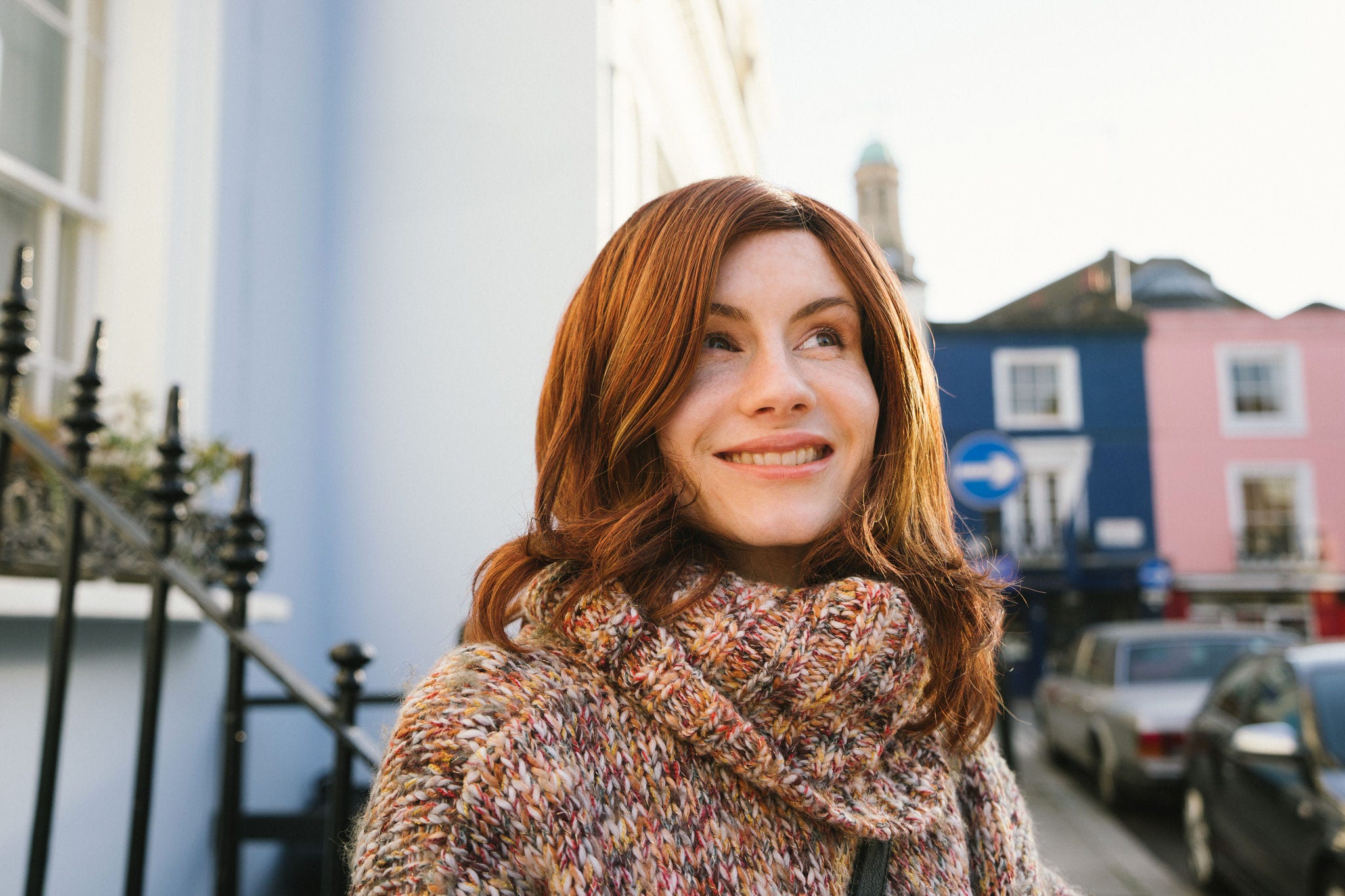 Cheerful transgender woman walking down the street in a residential district with colorful houses.