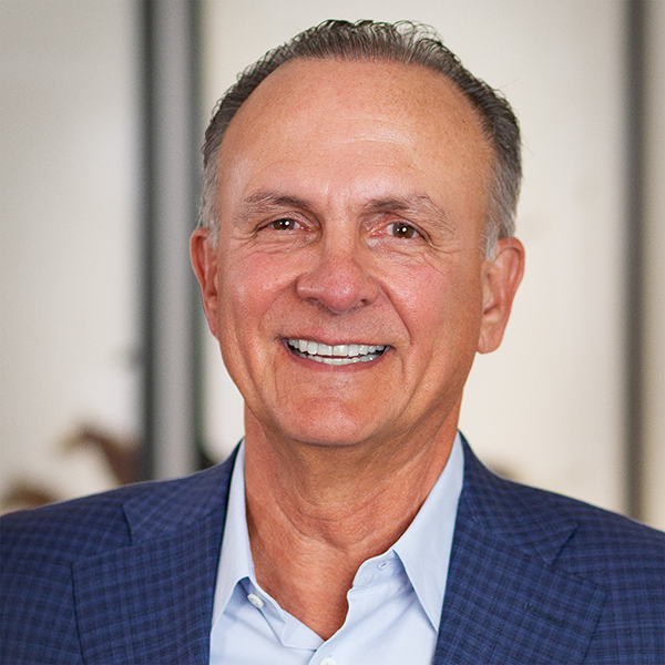 Professional headshot of a smiling man in a blue suit