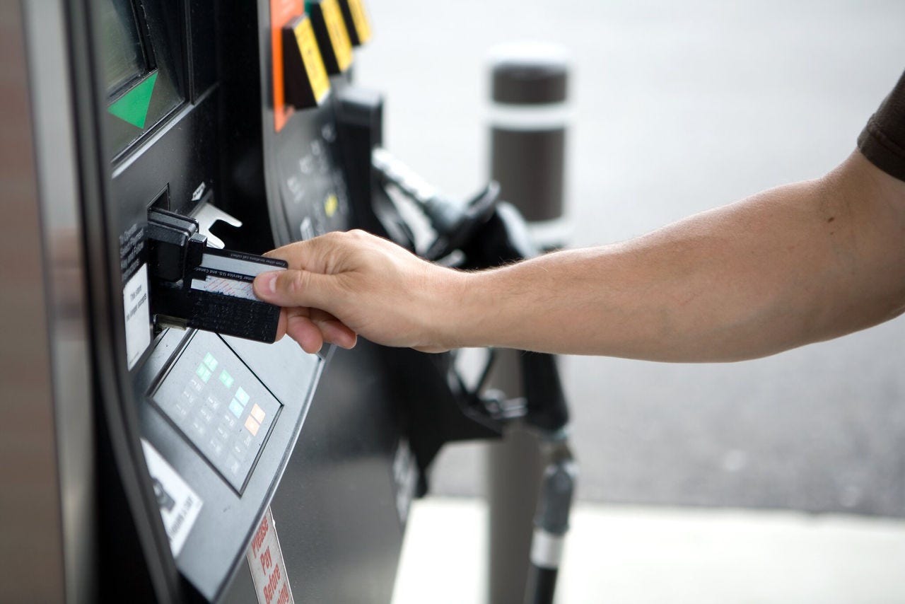 Man inserting a credit card into a gas station payment terminal