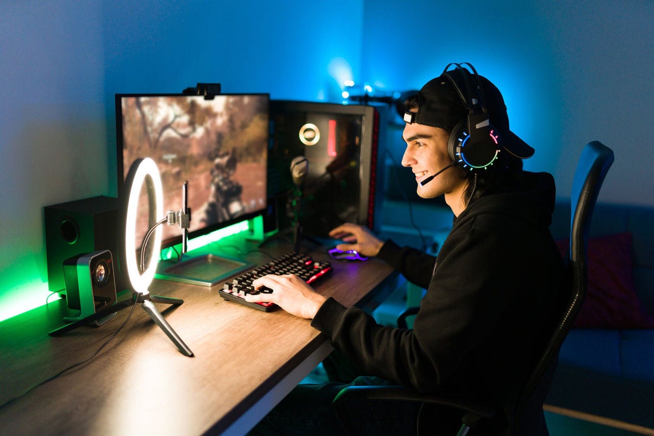 A gamer wearing a headset and streaming live while playing a video game on a dual monitor setup