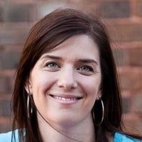 A woman smiling in front of a brick wall