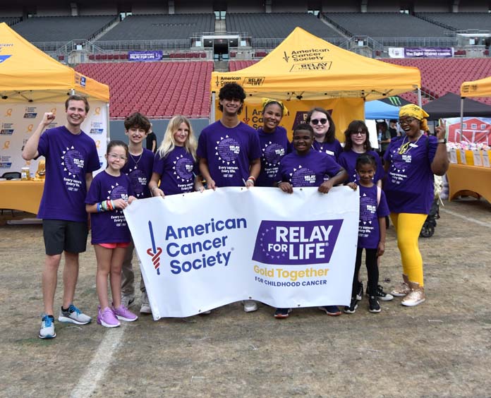 Group of individuals holding up a banner with The American Cancer society, Gold Together and Relay for Life logo