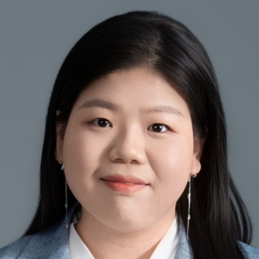 Headshot of postdoctoral fellow Ruiqi Jin, PhD, in a blue-gray blazer, white blouse, and silver earrings