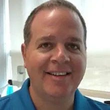 white man with high forehead and teal, collared  shirt 