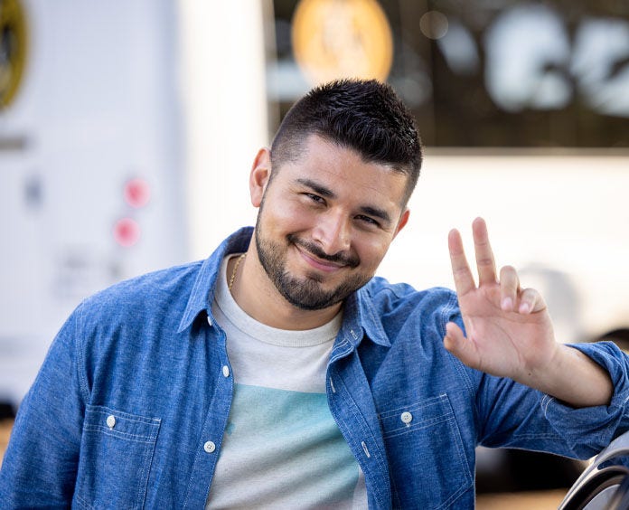 A male volunteer posing for a photo with the peace sign up