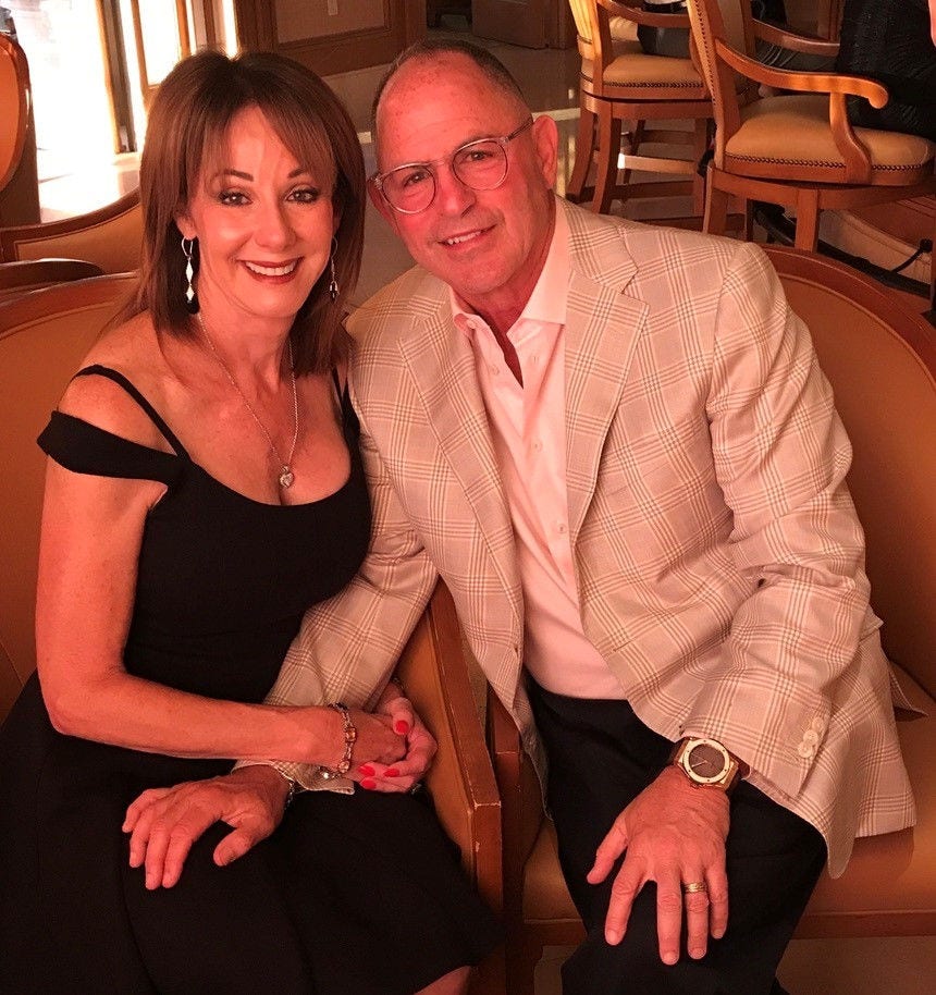 Smiling couple dressed elegantly, seated together indoors