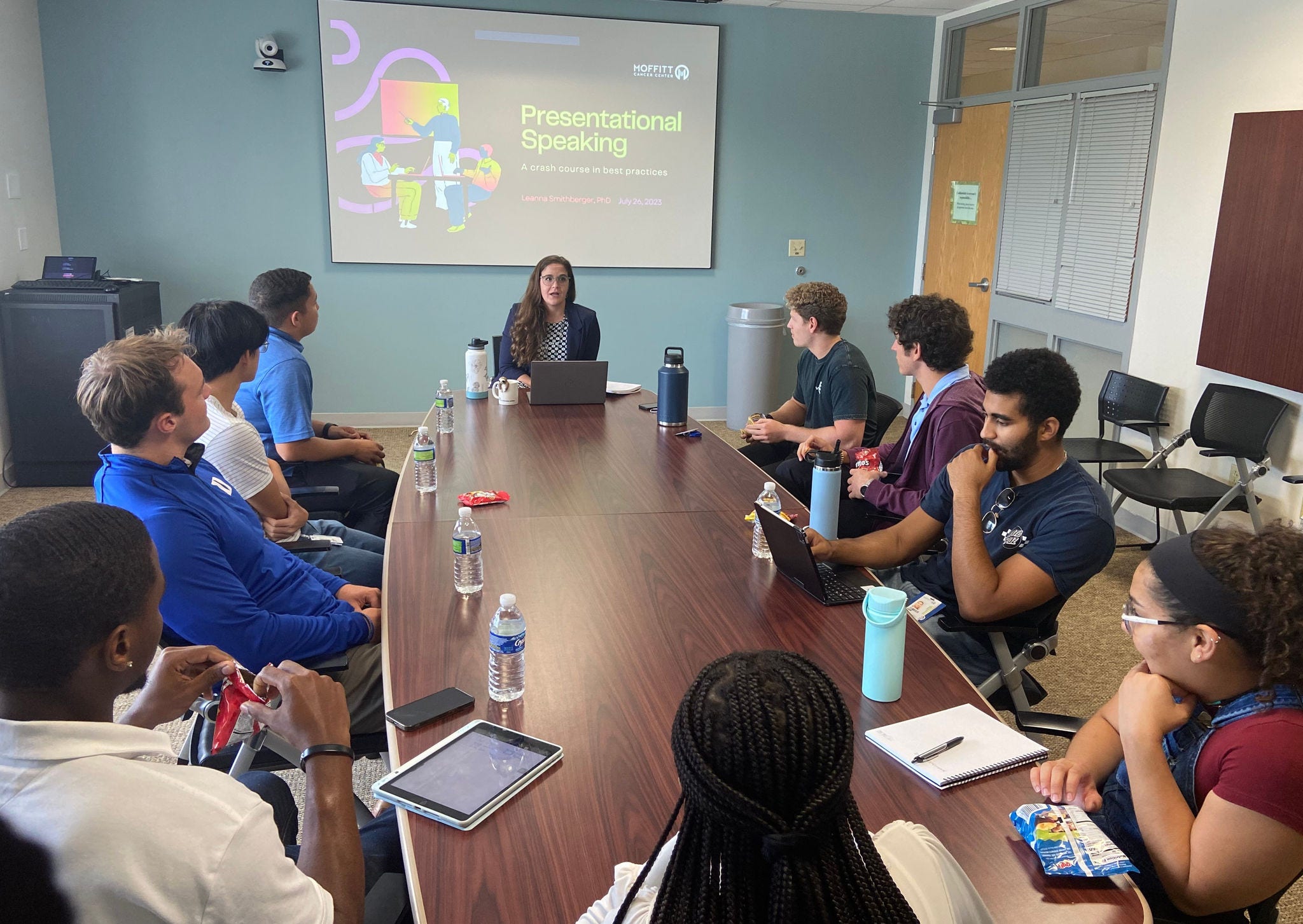 table with students sitting facing screen that says Presentational Speaking