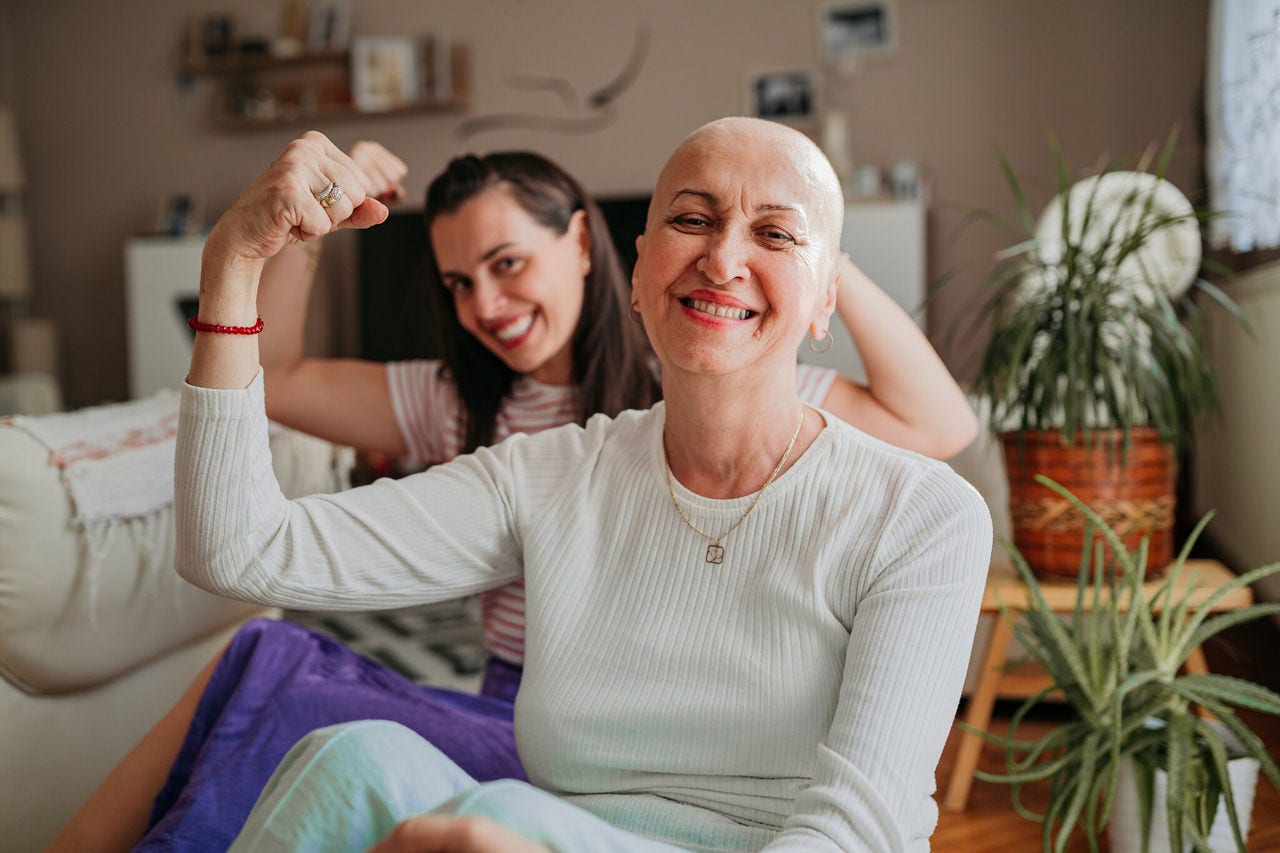 Bald woman smiling with family, celebrating strength and recovery at home.