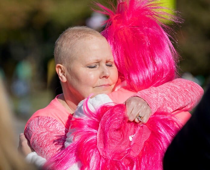 两名身穿粉色衣服的人在“对抗乳腺癌”活动中拥抱
