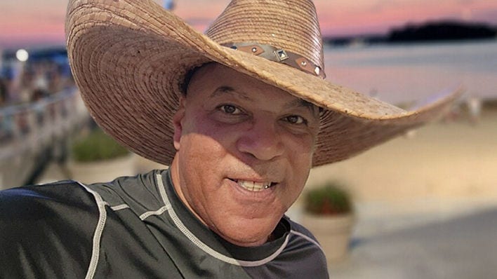 Smiling man in a cowboy hat at the beach during sunset