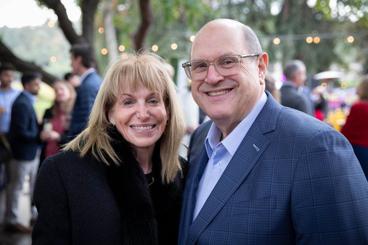 A smiling white man and woman standing together at an outdoor event.