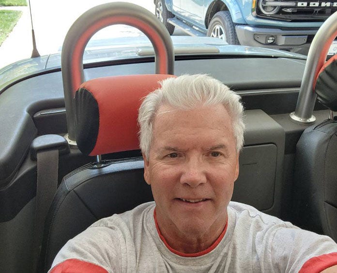 A man(Gerald) sitting in the drivers seat of a vehicle he donated to the American Cancer Society Cars for a Cure program 