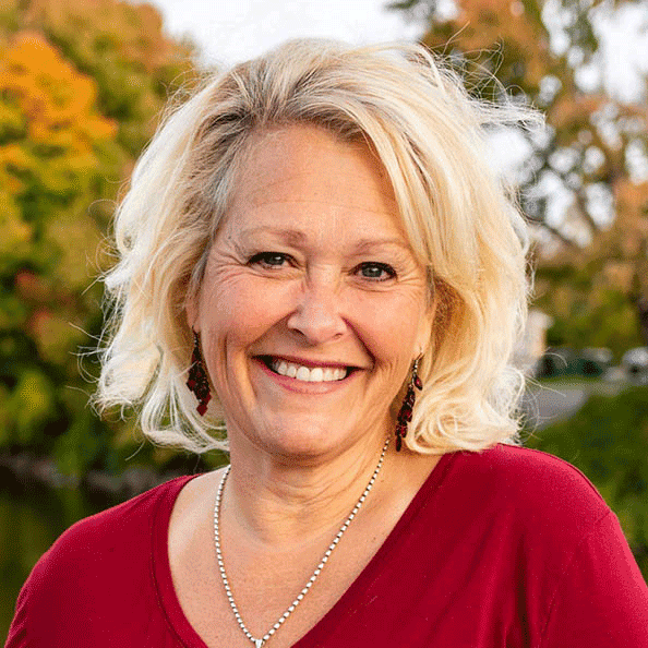 Headshot of a woman with blonde hair, smiling outdoors