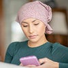 A woman wearing a headscarf, looking at her phone.