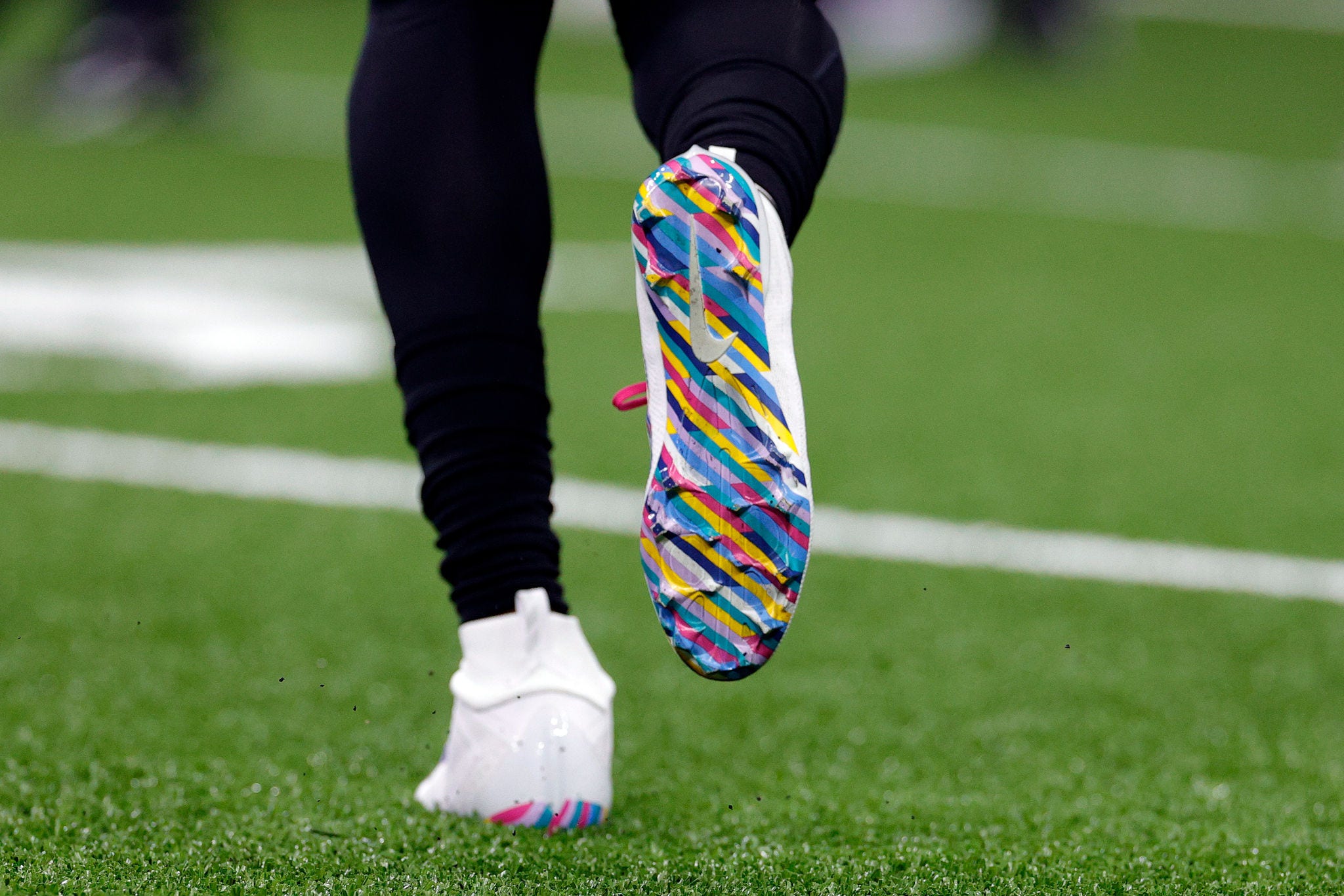 a close-up of a player's colorful cleats on a football field