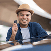 hispanic man holding up car keys while standing beside a car