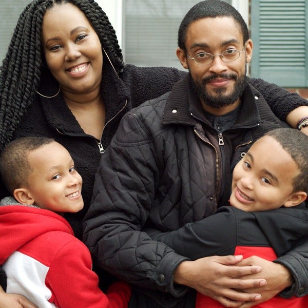 戴眼镜的黑人男子拥抱妻子和孩子