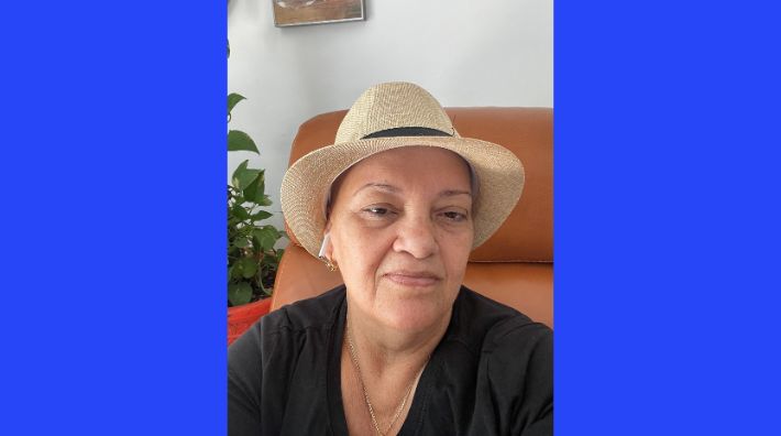 Marlen Capote Camacho smiles while wearing a tan straw hat