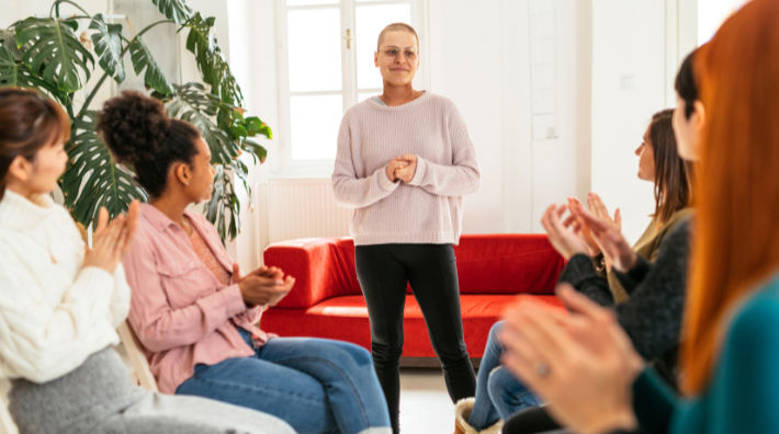 A group of women clapping for another woman who is standing.